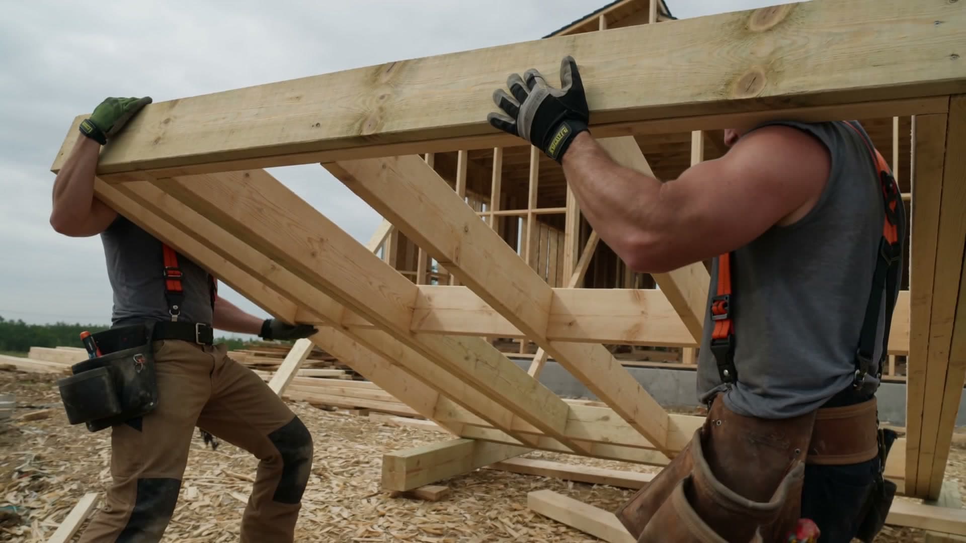 Two framers lifting a roof truss into place, a frame from an 8E Media spot